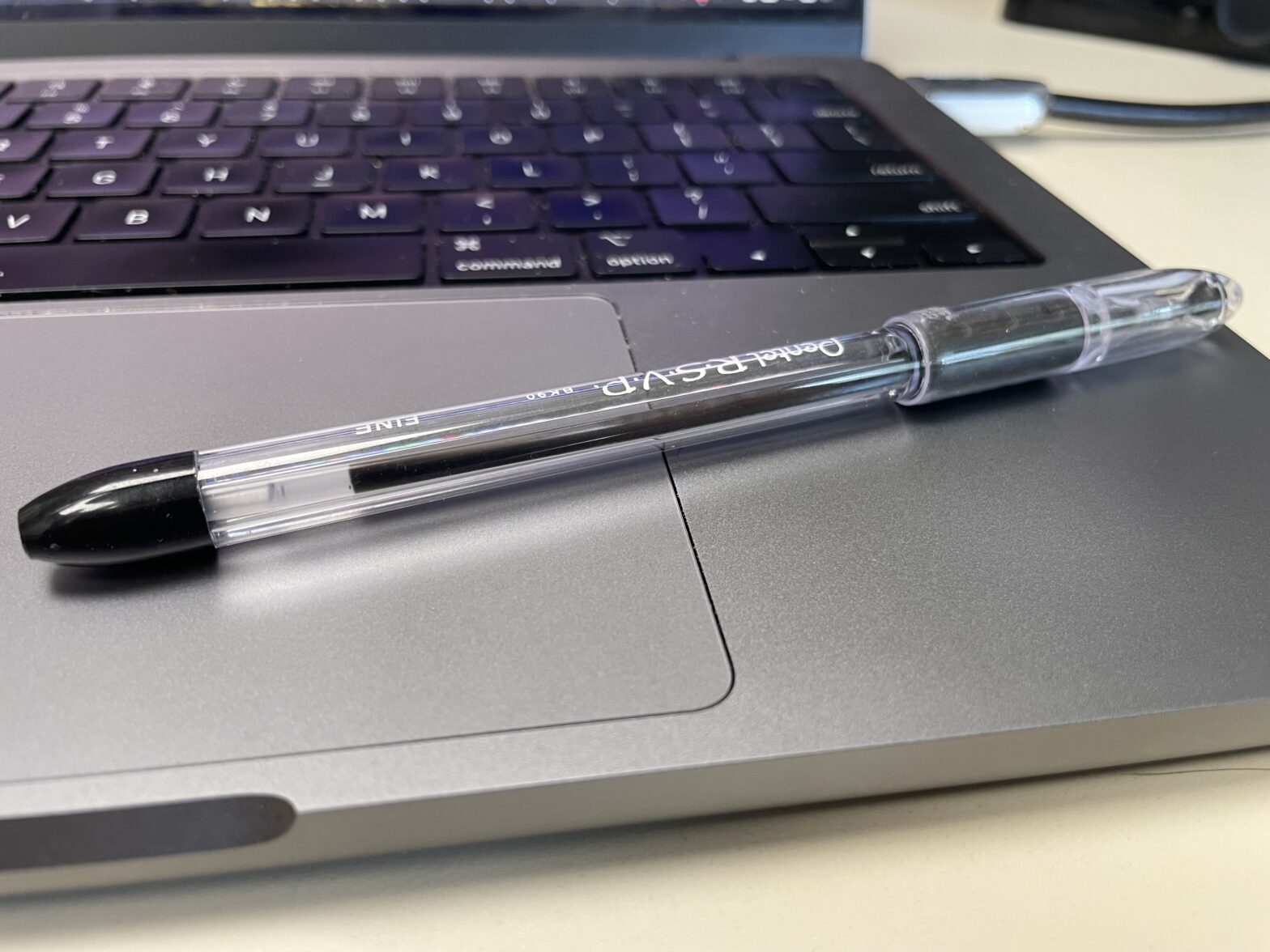 A pen sits on the trackpad of a laptop.