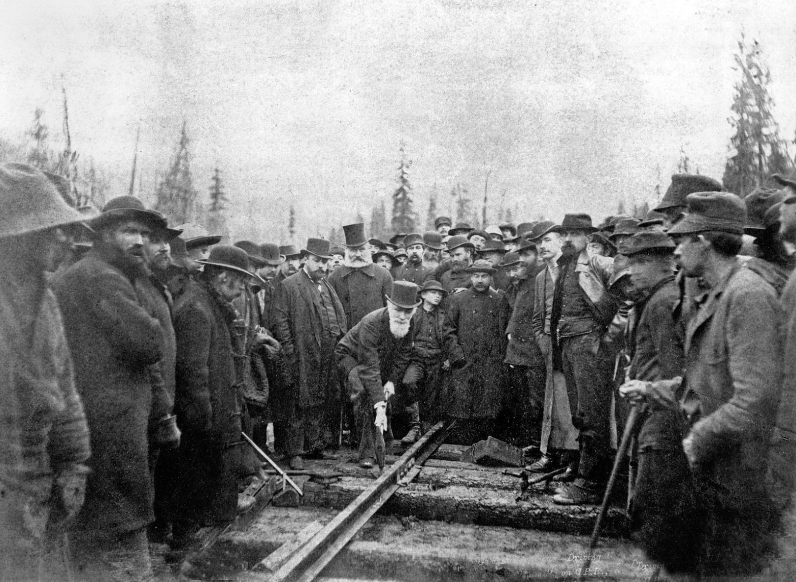 Sir Donald Smith drives the last spike at Craigellachie from the wikipedia page. Last Spike of the CPR - Craigellachie, British Columbia, Canada. Donald Alexander Smith driving the last spike of the Canadian Pacific Railway. Also in the photo are (generally left to right) Albert Bowman Rogers (Surveyor), Michael Haney (Contractor), William Cornelius Van Horne (CPR Manager), Sir Sandford Fleming, Edward Mallandaine (teenager), Henry Cambie (engineer), John Egan (General Superintendent), Sam Steele (NorthWest Mounted Police), James Ross (engineer). The man at the rear of the photo, just right of centre, with a white cowboy hat and moustache, is reputed to be Tom Wilson, guide & outfitter & the first white man to see Lake Louise.